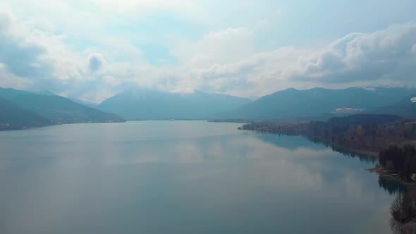 Slow aerial pan, showing the lake Tegernsee with the Wallberg in the background on a spring day.