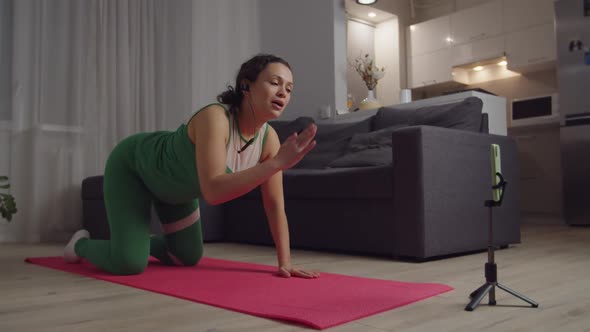 Female Trainer Holding Online Video Tutorial Showing Cat Cow Exercise