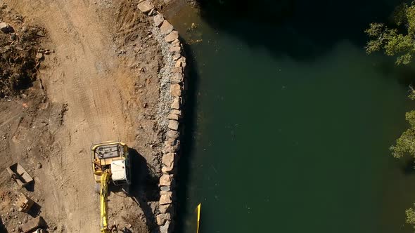 A large excavator repairing a section of river damaged by a flood caused by a tropical cyclone