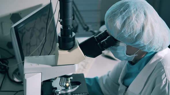 Female Pharmacist Works with Modern Microscope.