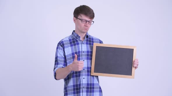 Happy Young Hipster Man Holding Blackboard and Giving Thumbs Up