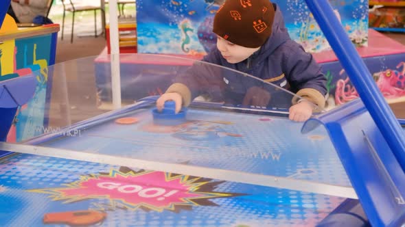 A Boy of 4 Years Plays Air Hockey Quickly Beats the Puck