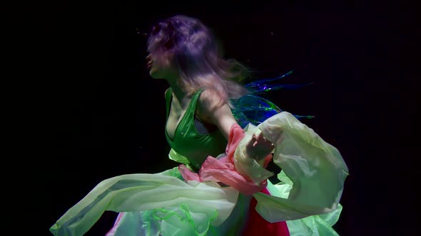 Young Charming Woman Is Submerging in Depth of Aquarium, Playing with Multicolored Fabric