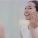 Fresh healthy skin of Asian girl looking at mirror, applying facial moisturizer on her face. - VideoHive Item for Sale