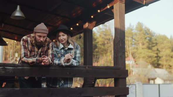 Couple Standing on Wooden Terrace Outdoors and Talking