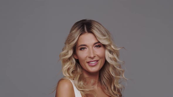 Studio portrait of young and beautiful blond woman over grey background.