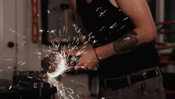 Sparks fly off angle grinder used by man with safety goggles in garage