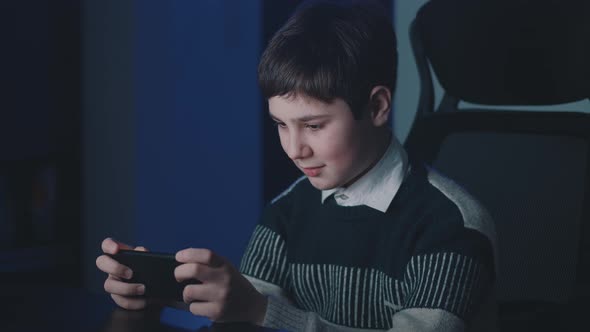 Portrait of Boy 1213 Years Old Playing on His Smartphone Exciting Mobile Application Game Clenching