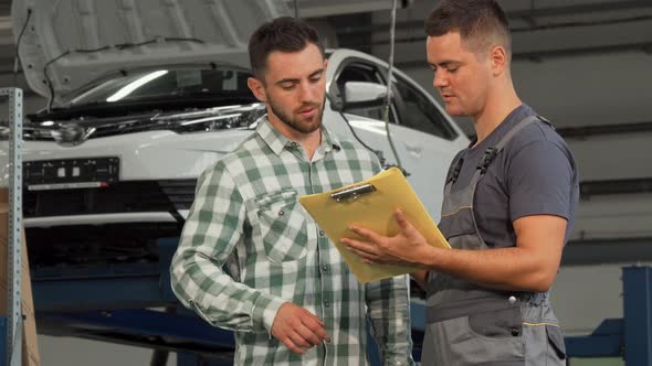 Happy Man Signing Papers After Getting His Car Repaired at Service Station