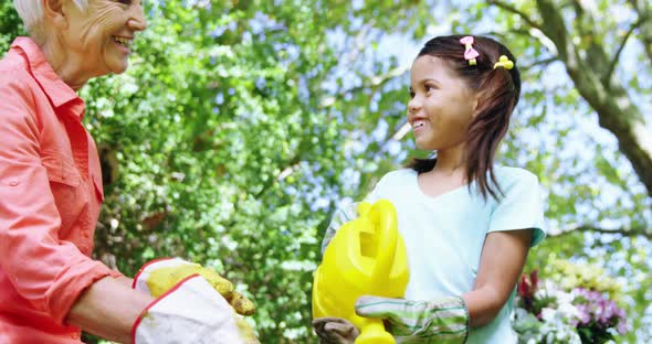 Grandmother and grand daughter watering plants