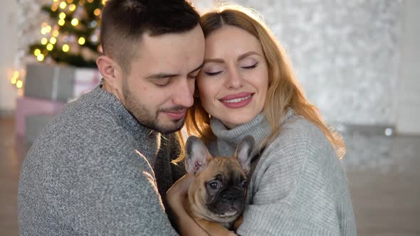 A Couple in Love Holds Their Dog in Their Hands