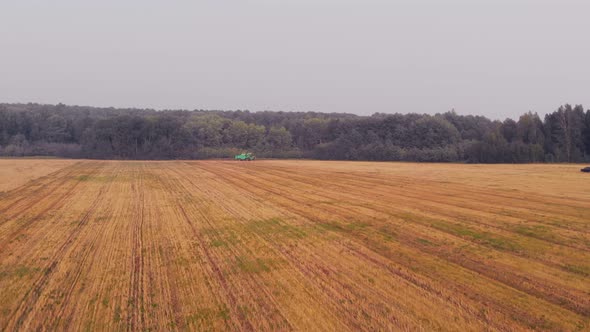 The Drone Flies Over an Agricultural Field After a Combine Harvester That Has Collected Wheat and