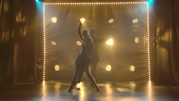 Young Couple of Ballroom Dancers Dancing Passionate Latin American Dance Cha Cha Cha. Silhouettes