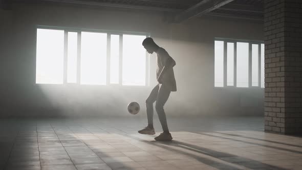 Black Boy Football Soccer Player Practicing Tricks Kicks and Moves with Ball Inside Empty Covered