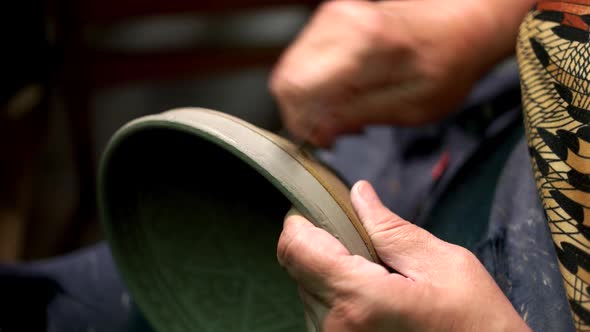 Potter Cleaning Clay Bowl at Workshop