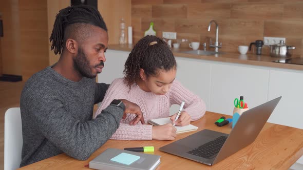 Happy African American Father Helps to Study Online to His Teen Age Daughter
