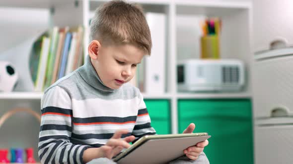 A Child Boy is Using His Tablet to Surf the Internet