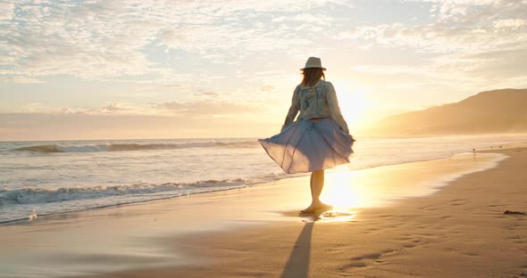 Cheerful Beautiful Woman Is Dancing on the Beach in Golden Sunset Light. USA