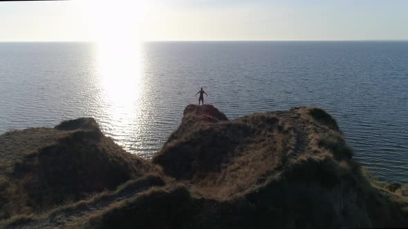 Man with Hope Looks Up at Sky and Raises Hands Towards Heaven in Bright Sunshine on River Bank