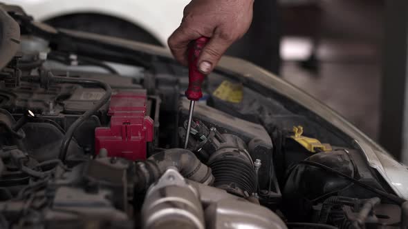 Car Master Repairs Car Engine With Screwdriver In Repair Shop