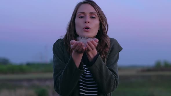 Girl Blows Away Seeds Dandelion with your Hands on Camera