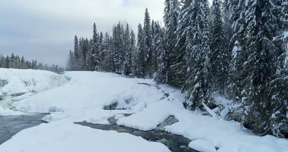 Stream flowing through snowy forest 4k