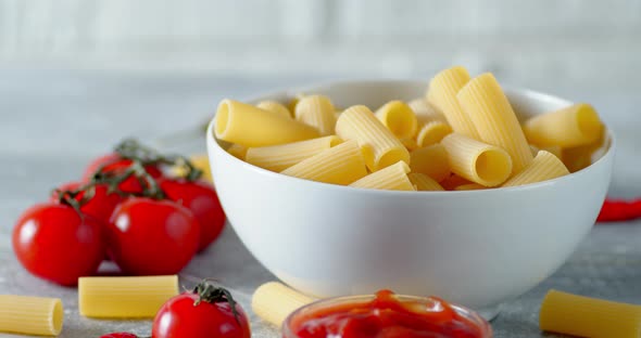 Bowl with Dry Pasta Cannelloni and Tomatoes Slowly Rotates. 