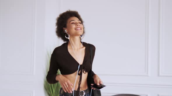 A smiling woman walking while listening the music using wired earphones