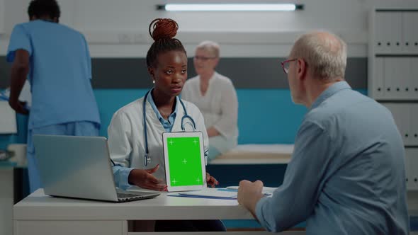 Medic Showing Green Screen on Tablet to Senior Man