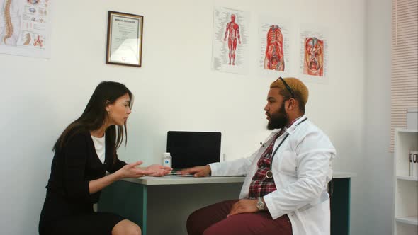 Angry Female Patient Shouting at Doctor Who Is Offering Her Glass of Water