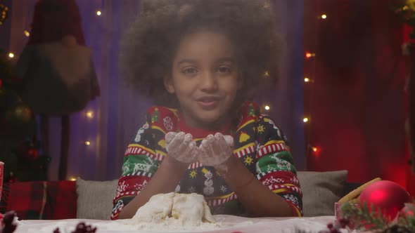 Little African American Girl in New Years Print Sweater Has Fun Blows Flour Off Her Hands and