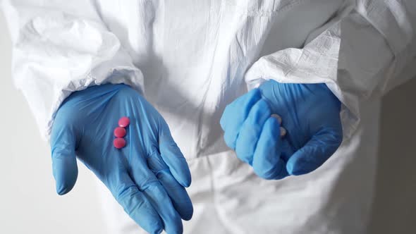 Doctor Shows Various Pills. Doctor's Hands in Protective Gloves Close-up. Concept - a Cure for a New