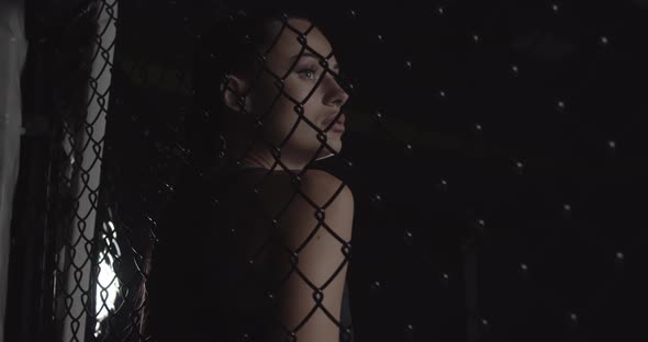 Modern Fashionable Woman Behind a Tatami Net in the Dark with a Lighted Face Looking at the Camera