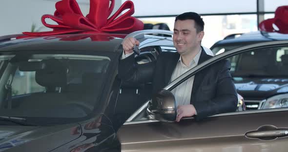 Portrait of Young Caucasian Man Standing at New Car and Bragging Keys. Happy Brunette Businessman