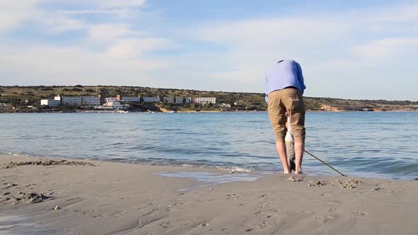 LONG SHOT of father playing with his son on the beach, holiday, near the shore line carrying a net