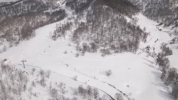 Flying over rope-way with gondolas at mountain resort Crystal Park in Bakuriani. Snowy winter day.