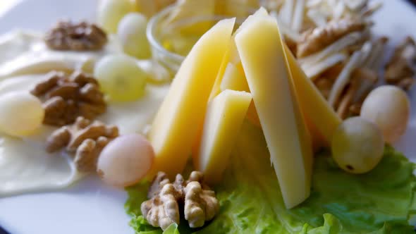 Cheese Plate Served with Different Types of Cheese Honey Walnuts and Grapes