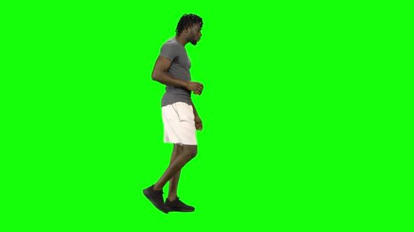 African American Man Walking and Drinking Coffee at Green Screen, Chroma Key. Profile View.