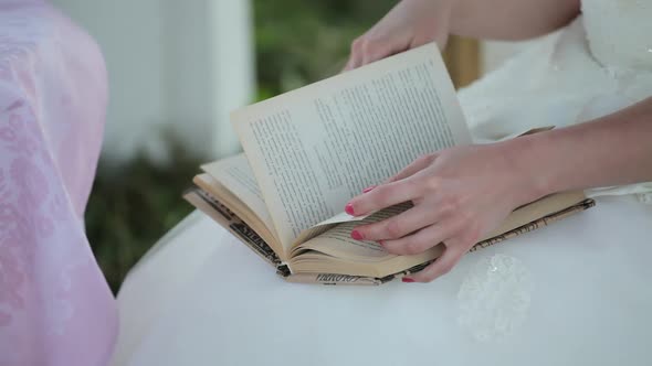 a girl in a white dress reads a book