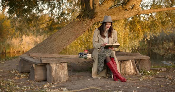Woman Sitting on a Bench Under a Tree with Books