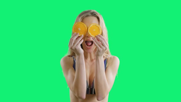 Young Beautiful Girl Is Smiling with Oranges in Hands on an Green Screen Background. Happy Healthy