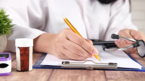 Female Doctor Hand Writing Prescription on Desk Close Up