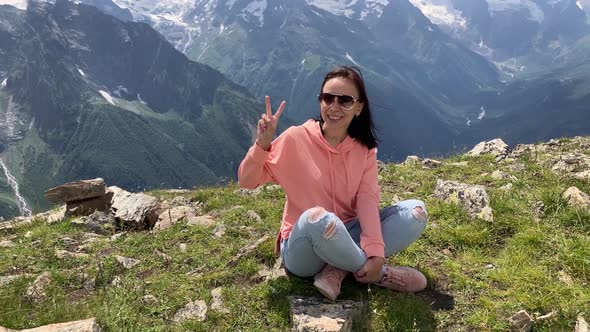 Young Woman Sitting on Rock and Looking at Mountain Landscape