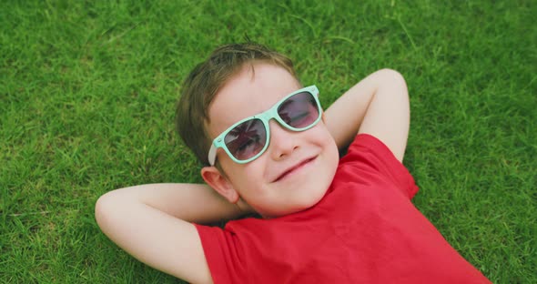 Happy Cute Child Lies on the Green Grass a Little Boy in Sunglasses Lies on the Grass Resting