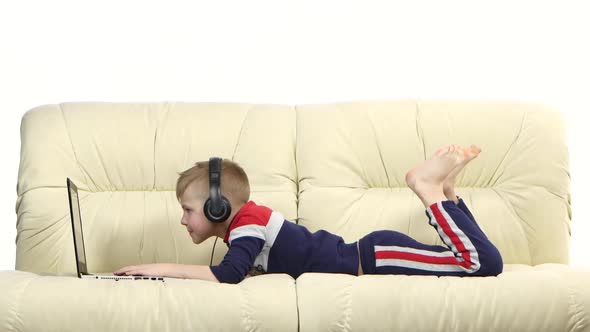 Teen Playing Online Games on Laptop in Headphones on Couch