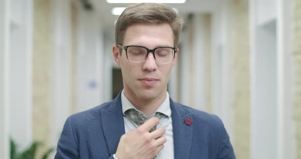 Close-up Portrait of Confident Handsome Caucasian Man in Eyeglasses Posing in Office Corridor