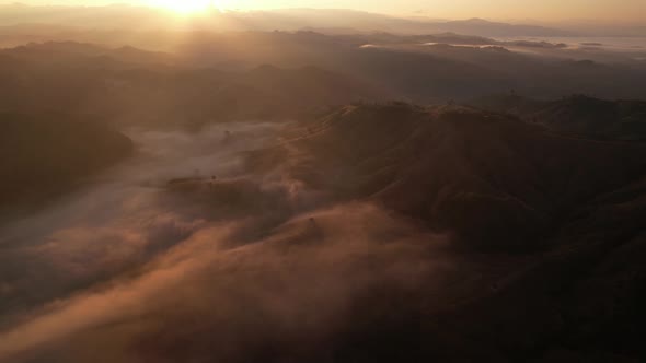 Aerial view of sunrise with fog above mountains