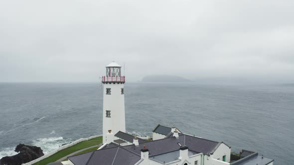 Drone pull out aerial shot of lighthouse in Ireland