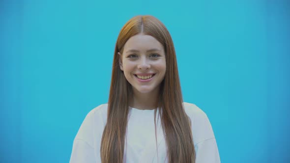 Beautiful Red-Haired Girl Smiling Against Blue Background, Healthy Lifestyle