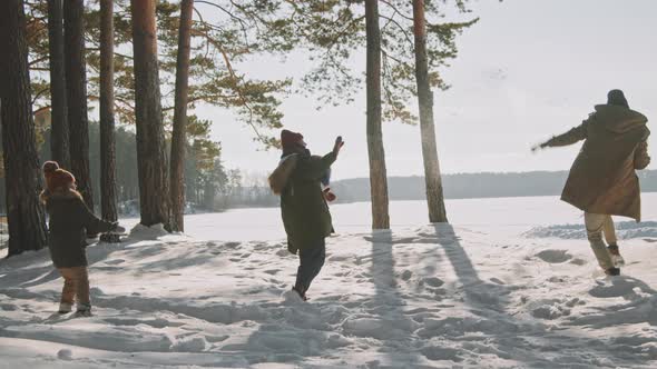 Family Throwing Snowballs on Sunny Winter Day